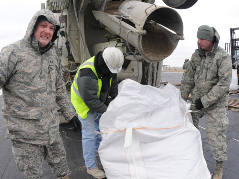 Tech Sgt. Kevin Reinhardt, left, and Staff Sgt. Anthony Salquist, both of the 119th Logistics Readiness Squadron, fill one-ton sandbags with the help of civilian contractor Dan Brovold and his cement truck, in preparation for implementation in flood fighting operations March 19 at the North Dakota Air National Guard, Fargo, N.D.  The large sandbags are being readied for UH-60 helicopter sling-load operations, should they be necessary in emergency battling rising flood waters anywhere in eastern North Dakota.