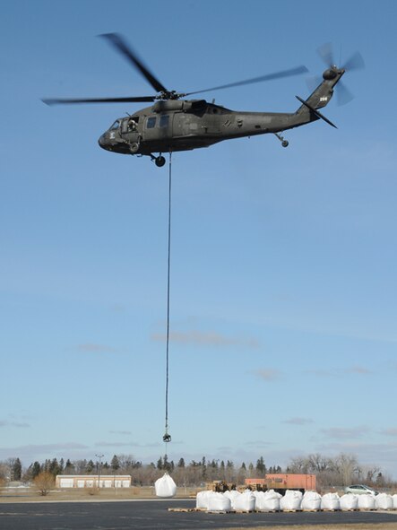 A Minnesota Army National Guard UH-60 Blackhawk helicopter practices sling load operations March 19, Fargo, N.D.   Sgt. 1st Class Todd Suderheimer, of the 2/147th Aviation Battalion, trains North Dakota Air National Guard members on the ground how to link a 1.5 ton sandbag unto the helicopter cable so that the sandbag can be transported to a simulated flood fighting location. The training and placement of the large sandbags are in preparation for UH-60 helicopter sling-load flood operations, should they be necessary in an emergency situation with rising flood waters anywhere in eastern North Dakota.