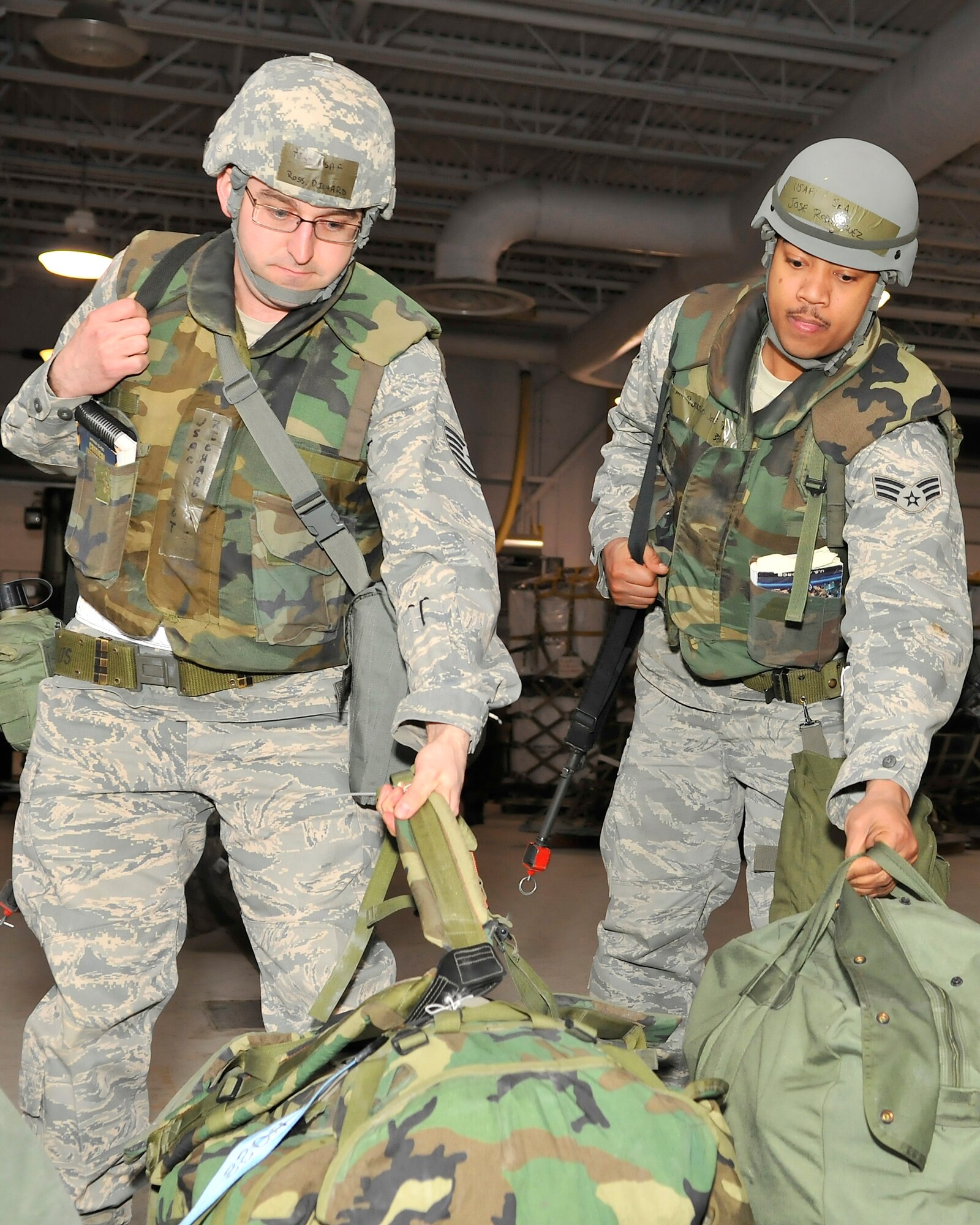 Tech. Sgt. Ross Richard and Senior Airman Jose Rodriguez grab their mobility bags while processing through a deployment line at the Joint Mobility Center during exercise Golden Raven 10-2 Mar. 21, 2010, Eielson Air Force Base, Alaska. Sergeant Richard and Airman Rodriguez are both assigned to the 354th Civil Engineering Squadron. (U.S. Air Force photo/Staff Sgt. Christopher Boitz/released)