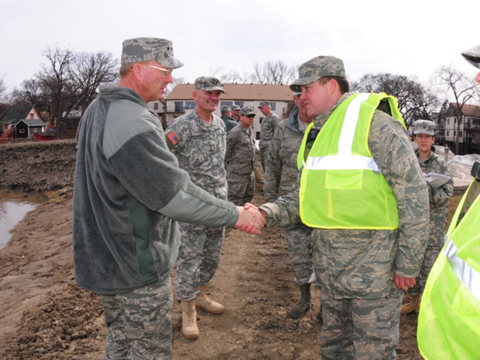 Gen. Craig R. McKinley, chief of the National Guard Bureau, shakes hands with Staff Sgt. Adam Kapaun, 119th Wing, while walking dike patrol near the Oak Grove Lutheran School on March 22.  McKinley spent the day in Fargo, N.D. visiting the Guardsmen currently on flood duty in the state. 