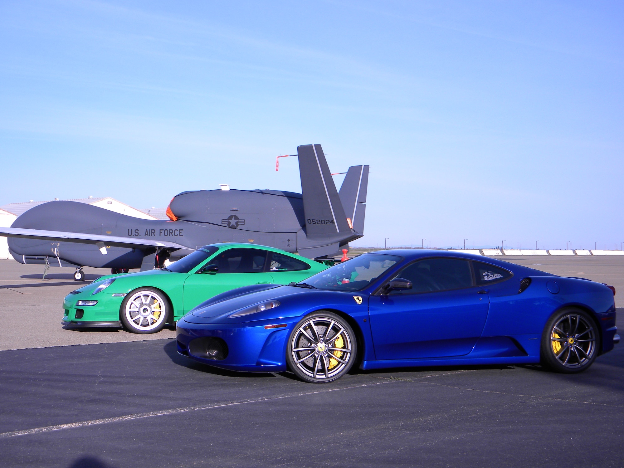 An RQ-4 Global Hawk yields the runway to a Porsche 997 GT3RS and a Ferrari F430 during filming of SPEED Channel's Battle of the Supercars. Both cars broke the 200 miles per hour barrier at Beale Air Force Base, Calif., March 14. (U.S. Air Force Photo/Dana Lineback)