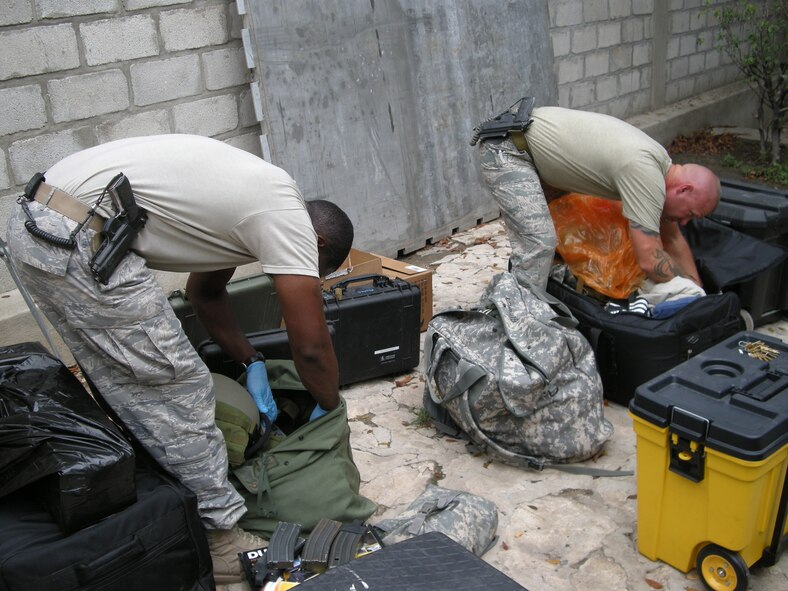 PETIONVILLE, Haiti -- Staff Sgt. Alfonte Thomas and Master Sgt. Donny Gallagher, 823rd Expeditionary Security Forces Squadron, inspect personal bags of military members redeploying here March 7. (U.S. Air Force photo by Senior Airman Jake Pratt)