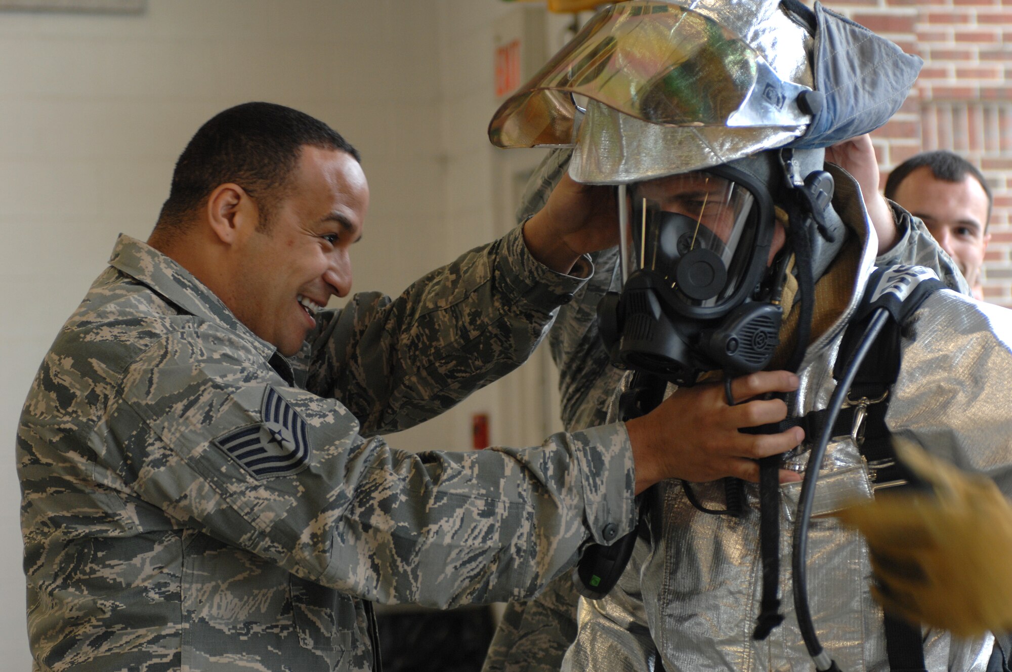 LANGLEY AIR FORCE BASE, Va. – Tech. Sgt. A.J. Eversley, 633d Civil Engineer Squadron station caption, helps Col. Matt Molloy, 1st Fighter Wing commander, don his fire protective equipment before a firefighter combat challenge test March 22.  Molloy finished the challenge in 7 minutes and 21 seconds. (U.S. Air Force photo/Tech. Sgt. April Wickes)