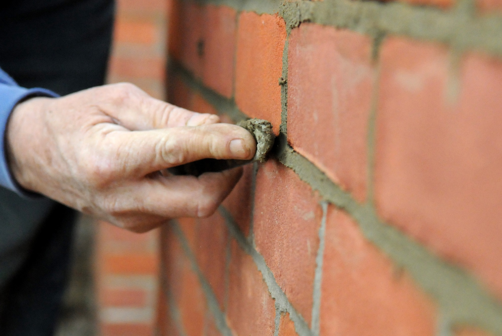 RAF MILDENHALL, England – Jesse Foreman, a contracted mason worker, smoothes out the mortar of a brick wall of the new conservatory and outside seating area being built at the Bob Hope Community Center March 18. (U.S. Air Force photo/ Staff Sgt. Jerry Fleshman)