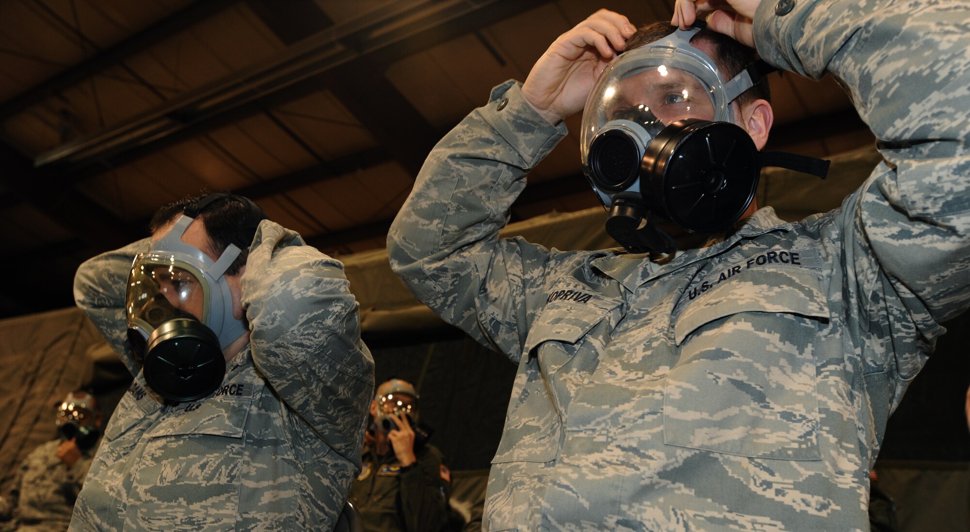 Senior Airman David Adams (left), 319th Communications Squadron radio technician, and Senior Airman Jacob Kopriva, 319th CS personal wireless communication service manager, don their gas masks March 18 on Grand Forks Air Force Base, N.D. The Airmen attended Chemical, Biological, Radiological and Nuclear training for their upcoming deployment. (U.S. Air Force photo by Airman 1st Class Amber Price)