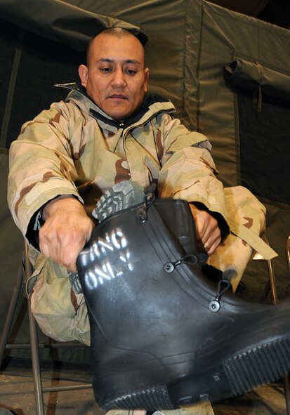 Tech. Sgt. Johnny Saldivar, 319th Public Affairs Photographer puts on his over boots March 18 on Grand Forks Air Force Base, N.D.  Sergeant Saldivar attended Chemical, Biological, Radiological and Nuclear training for his upcoming deployment. (U.S. Air Force photo by Airman 1st Class Amber Price)