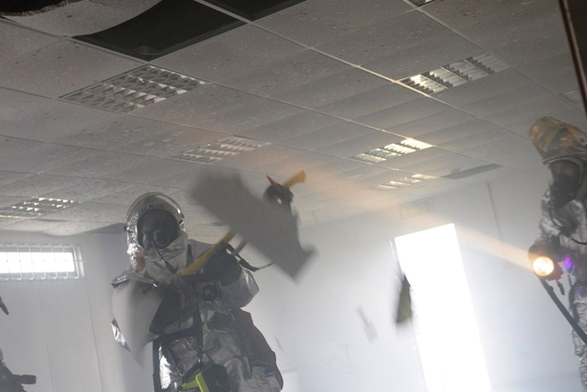 Ceiling tiles drop in a smoke-filled room as firefighters from the 100th Civil Engineer Squadron Fire Department test the condition of the structure of Building 804 after a mock fire March 18. The training exercise was part of a series of drills for the fire department's station chief to gain required certifications. The exercise provided an opportunity for training firefighters new to RAF Mildenhall. (U.S. Air Force photo/Karen Abeyasekere)