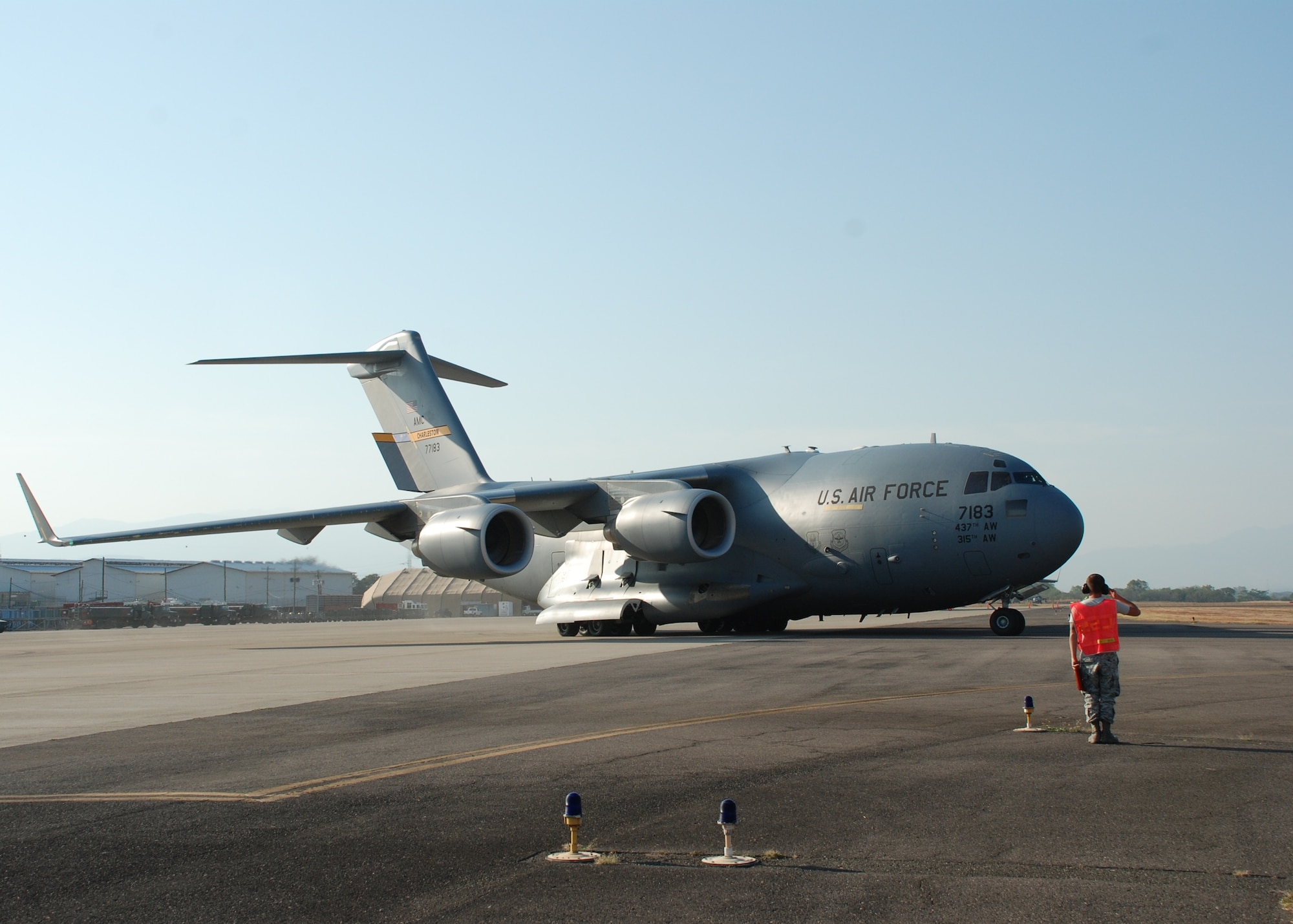 Senior Airman Kristopher Rainwater, 612th Logistics Readiness Squadron crew chief, salutes a C-17 Globemaster III as it departs Soto Cano Air Base, Honduras, with Joint Task Force-Bravo members deploying to Port au Prince, Haiti March 21. Team Soto Cano is sending 40 personnel and four UH-60s to support Joint Task Force-Haiti airlift operations as part of the disaster relief mission Operation Unified Response. (U.S. Air Force photo/1st Lt. Jen Richard)