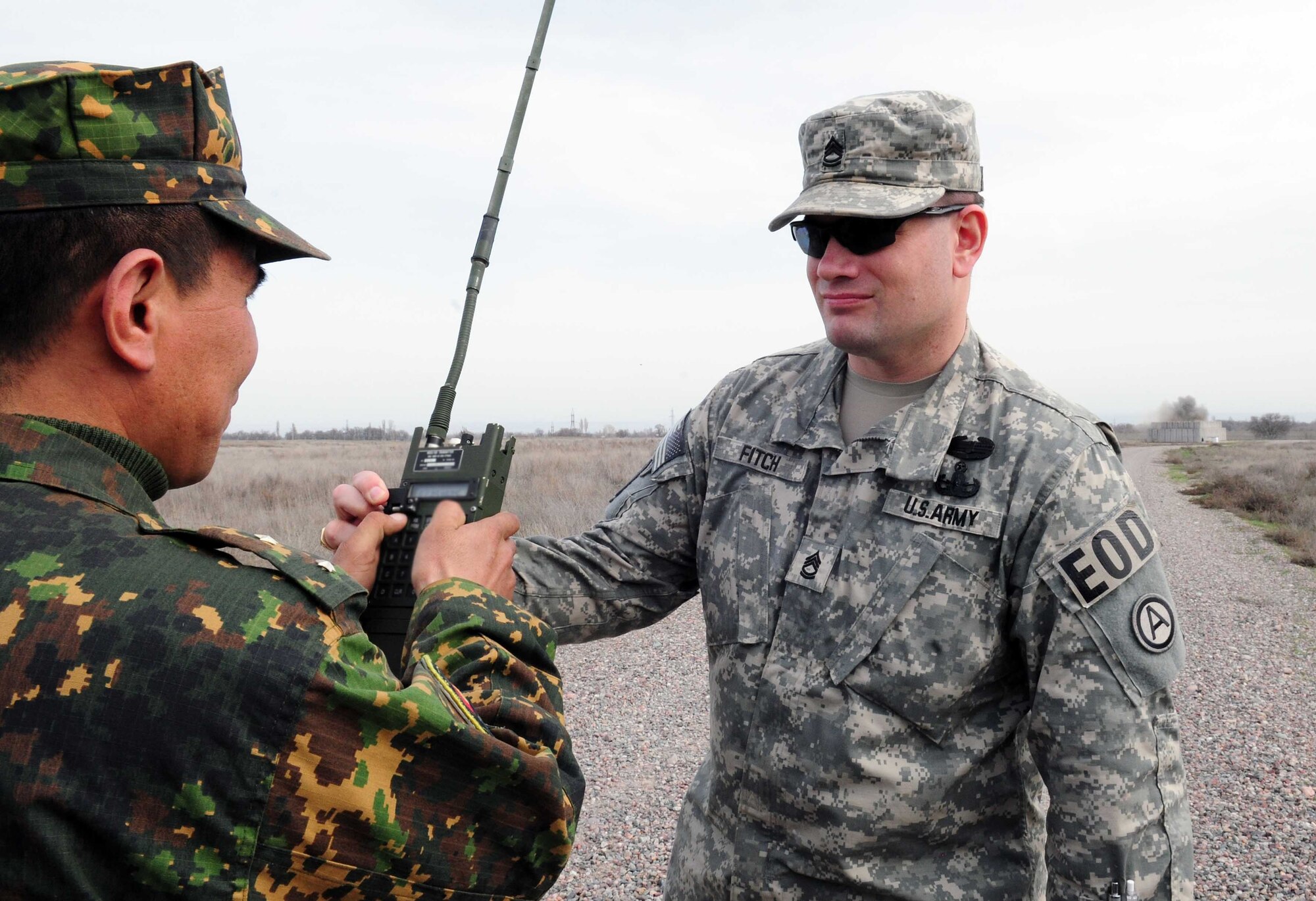 U.S. Army Sgt. 1st Class Stephen Fitch, U.S. Army Central explosive ordnance disposal operations NCO, helps Kyrgyz army Warrant Officer Sonynaliev Kazbek detonate explosives set in the EOD range via remote control during a subject matter information exchange with EOD Airmen from the Transit Center at Manas, Kyrgyzstan, March 17. (U.S. Air Force photo/Staff Sgt. Carolyn Viss/released) 
