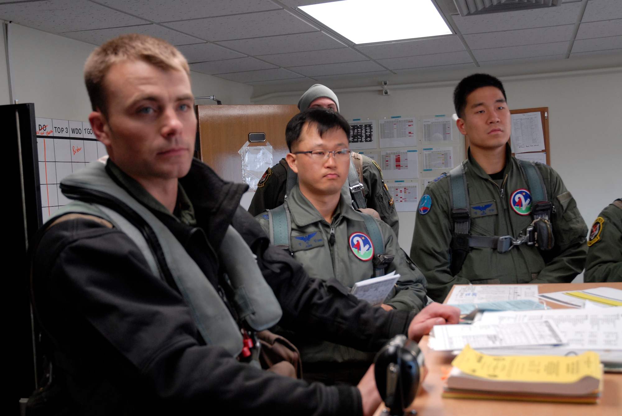KUNSAN AIR BASE, Republic of Korea -- Maj. Crispin Kretzmann, 391st Expeditionary Fighter Squadron, Capt. Sung Jin Jeon, 21st Fighter Squadron and Maj. In Chang Jung, 21st Fighter Squadron, receive their pre-flight briefing during a Buddy Wing Exercise March 16. The exercise partners Air Force and Korean pilots to operate effectively together for possible joint combat actions. (US. photo/Staff Sgt. Darnell T. Cannady)