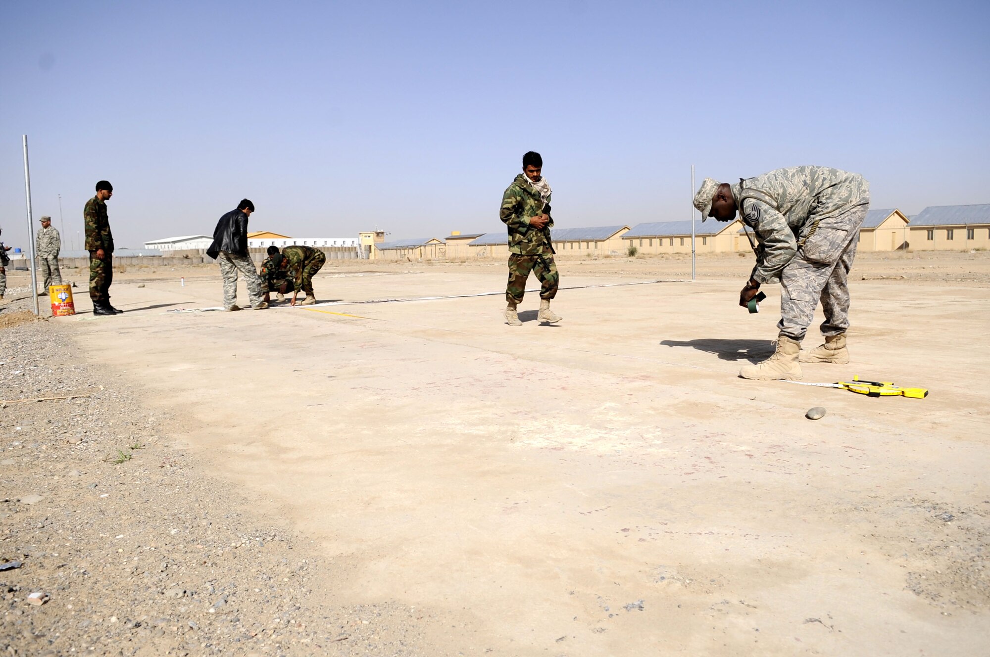 Technical Sergeant Vernon Jones, DCST—Task Force Phoenix medical advisor to the Kandahar Regional Military Hospital, assists members of the Afghan National Army as they construct a volleyball court to increase morale for their soldiers, March 1, at Camp Hero, Kandahar Airfield, Afghanistan. (U.S. Air Force photo by Senior Airman Nancy Hooks/Released)
