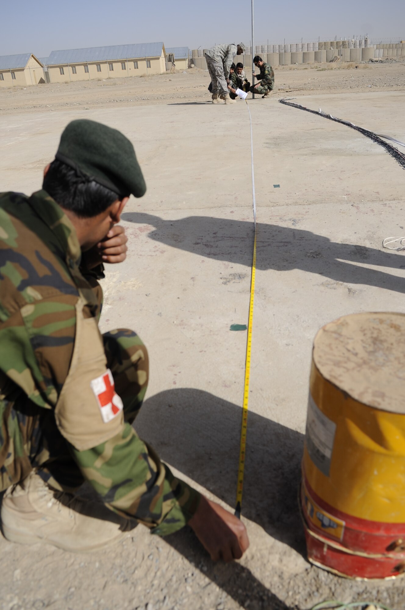 Technical Sergeant Vernon Jones, DCST—Task Force Phoenix medical advisor to the Kandahar Regional Military Hospital, assists members of the Afghan National Army as they construct a volleyball court to increase morale for their soldiers, March 1, at Camp Hero, Kandahar Airfield, Afghanistan. (U.S. Air Force photo by Senior Airman Nancy Hooks/Released)
