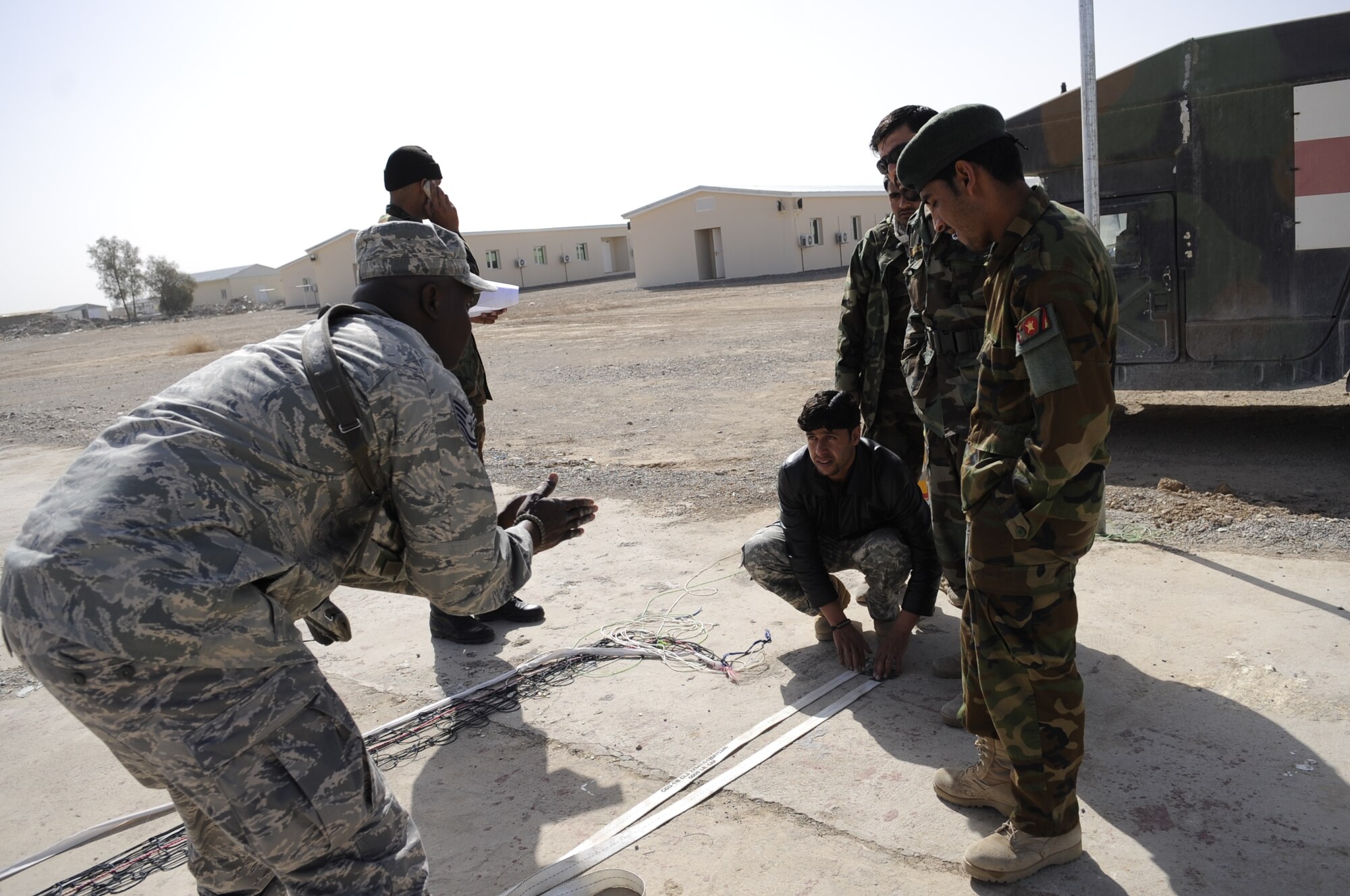 Technical Sergeant Vernon Jones, DCST—Task Force Phoenix medical advisor to the Kandahar Regional Military Hospital, assists members of the Afghan National Army as they construct a volleyball court to increase morale for their soldiers, March 1, at Camp Hero, Kandahar Airfield, Afghanistan. (U.S. Air Force photo by Senior Airman Nancy Hooks/Released)
