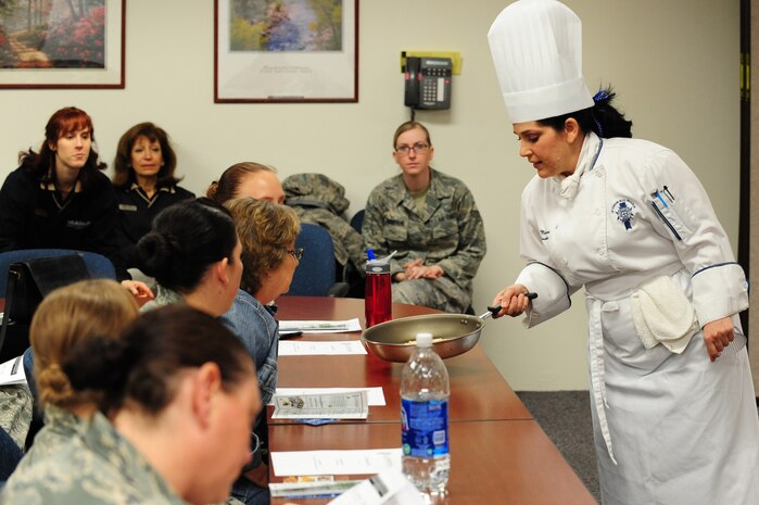 NELLIS AIR FORCE BASE, Nev. -- Chef presenter Elizabeth Martinez shows attendants of the Le Cordon Bleu cooking demo held at the Health and Wellness Center (HAWC) how to properly grease a pan before cooking "Fire Orange Chicken", March 11, 2010.  The cooking demo is  one of three events that the Nellis AFB nutrition department is hosting to promote National Nutrition Month during March.  (U.S. Air Force Photo by Staff Sgt. William P. Coleman/RELEASED)