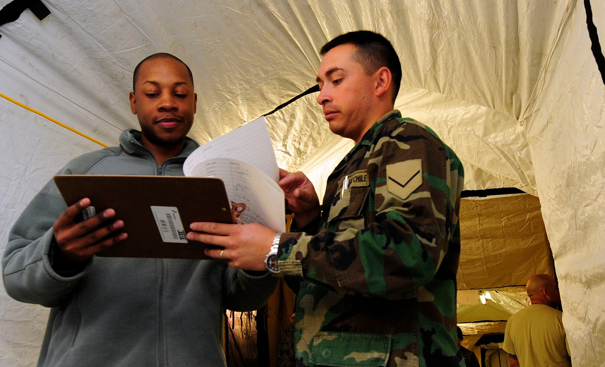 Staff Sgt. Michael Reese, 62nd Force Support Squadron, works with a Chilean military official as part of a commander's support staff in a tent in Chile following the earthquake that struck the country recently. (U.S. Air Force photo by Tiffany Trojca) 