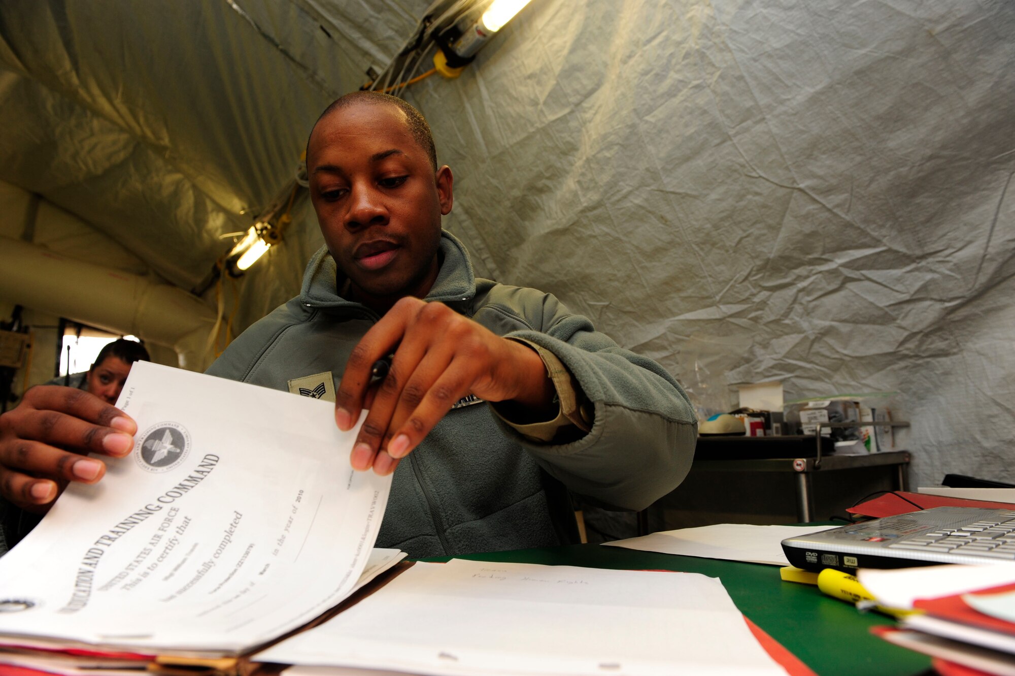 Staff Sgt. Michael Reese, 62nd Force Support Squadron, organizes paperwork as part of a commander's support staff in a tent in Chile following the earthquake that struck the country recently. (U.S. Air Force photo by Senior Airman Tiffany Trojca)