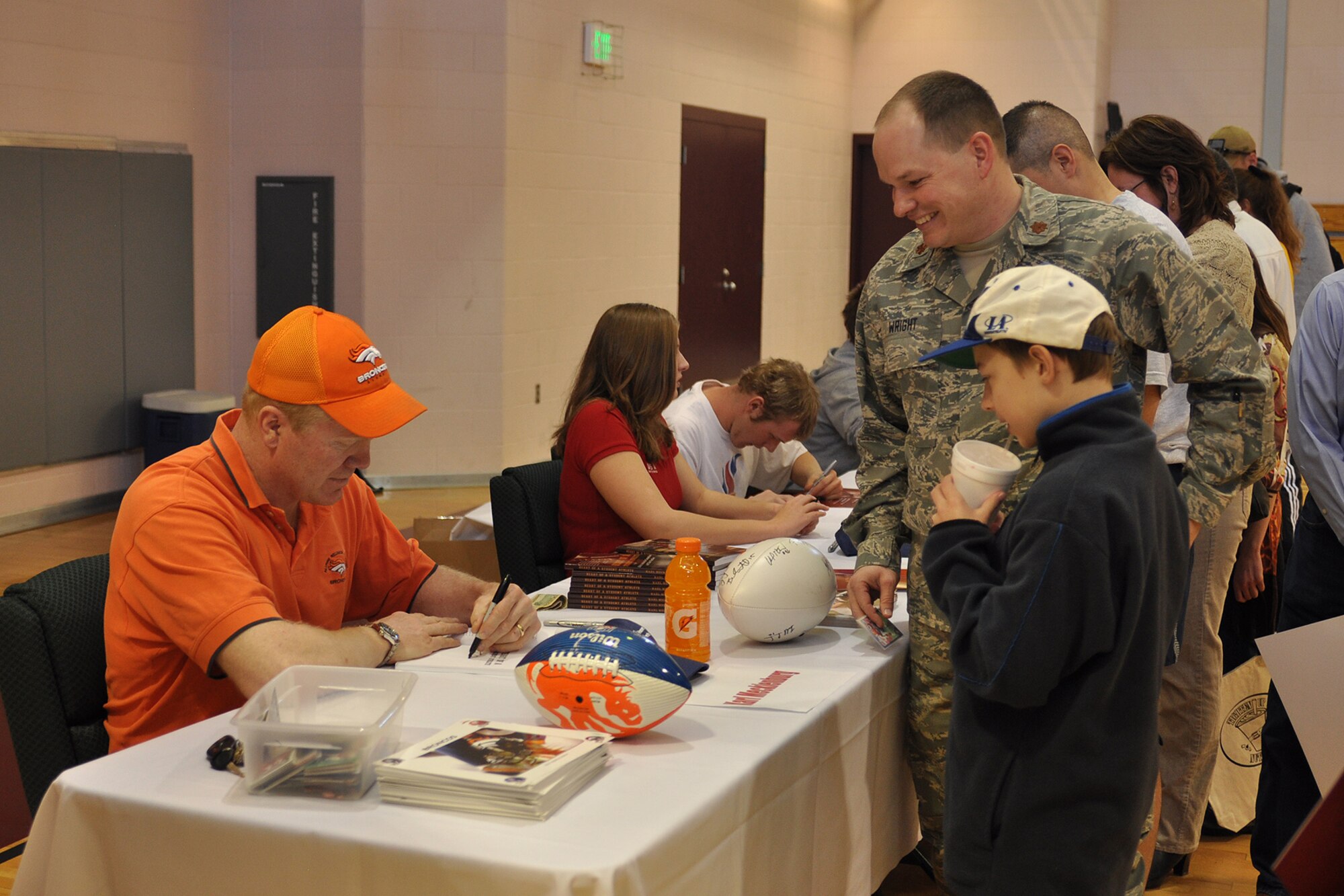 PETERSON AIR FORCE BASE, Colo. - Maj. Chad Wright, 21st Force Support Squadron, and his son Sam Wright, get an autograph from former Denver Bronco football player Karl Mecklenburg, March 12, at the grand opening celebration of the Tighten Up Nutrition juice bar in the Peterson Sports and Fitness Center, Building 560. Mr. Mecklenburg and members of the USA Paralympics Swim Team were on hand at the celebration to meet customers. The juice bar is reopened with new ownership, new specials and a new menu. (U.S. Air Force photo/Jennifer Brite)