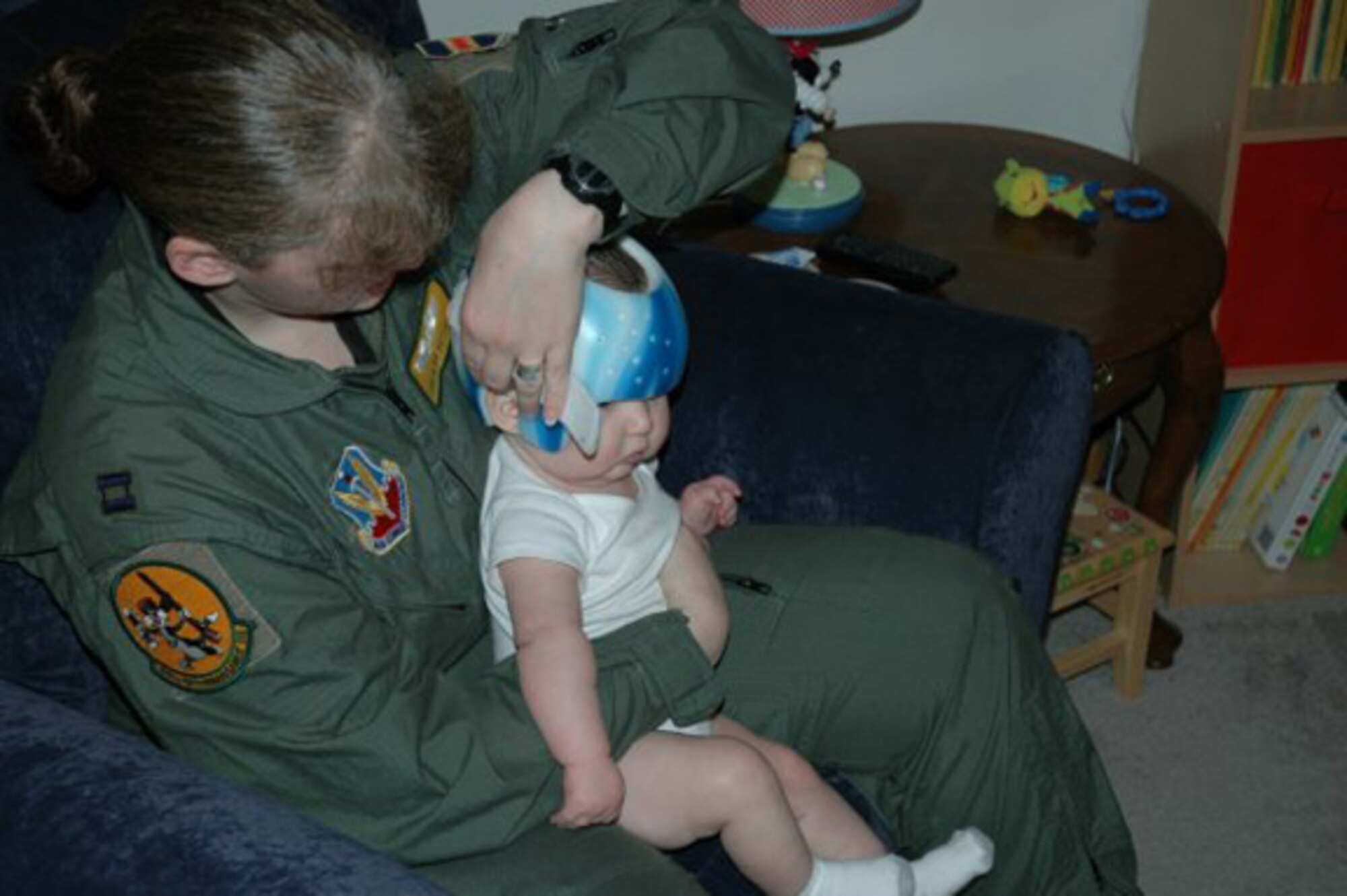 OFFUTT AIR FORCE BASE, Neb. -- Capt. Sonja Hosler, the mobility flight chief for the 45th Reconnaissance Squadron, holds her six-month-old son, Clark Alexander, while she carefully removes his cranial helmet. Clark required the helmet to correct a severe flat spot on his head, officially known as plagiocephaly Captain Hosler and her husband Adam were able to purchase the helmet after receiving a $2,500 grant from the Air Force Aid Society. U.S. Air Force Courtesy Photo