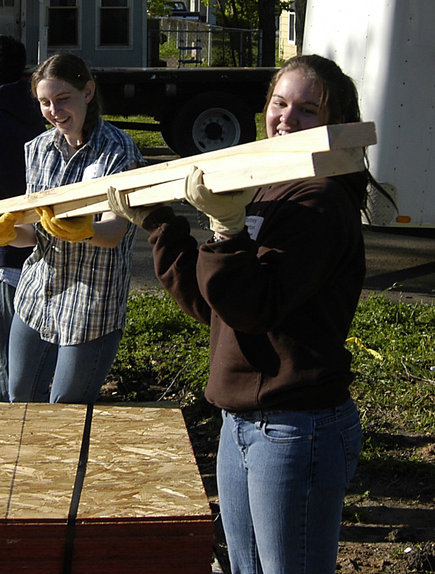Cadet 3rd Class Courtney Pinkerton (front) and Cadet 2nd Class Bridget Flatley pass boards along a human conveyor belt from a shipping vehicle to a house as part of a Habitat for Humanity project in Victoria, Texas, March 22, 2010. The project is one of several undertaken by cadets as part of Alternative Spring Break. The cadets are assigned to Cadet Squadron 37. (U.S. Air Force photo/John Van Winkle)