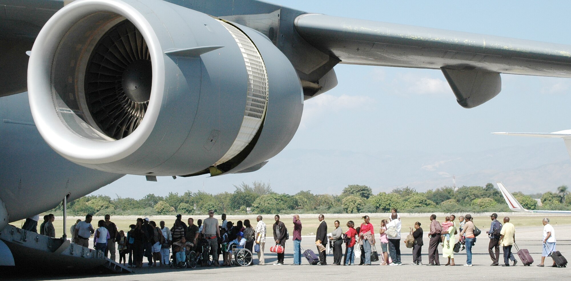 Airmen assigned to the 621st Contingency Response Wing from Joint Base McGuire-Dix-Lakehurst, N.J., assist in the loading of evacuees at Toussaint L'Ouverture International Airport Jan. 23, 2010, in Port-au-Prince, Haiti. Airmen responded in the aftermath of a 7.0 magnitude earthquake that crumbled most of the surrounding area, killing hundreds of thousands and displacing millions from their homes. (U.S. Air Force photo/Tech. Sgt. Bryan Gatewood)