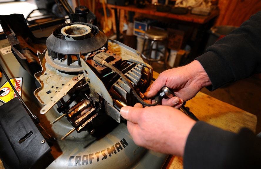 OFFUTT AIR FORCE BASE, Neb. -- Rocky Rengo, an Equipment Rental assistant, changes a spark plug as part of routine and seasonal maintenance on a lawnmower at the Equipment Rental facility, located on Butler Boulevard March 19. Equipment Rental offers a wide array of items for recreational use and yard maintenance, as well as a small machine shop that services most small motor items. U.S. Air Force photo by Josh Plueger
