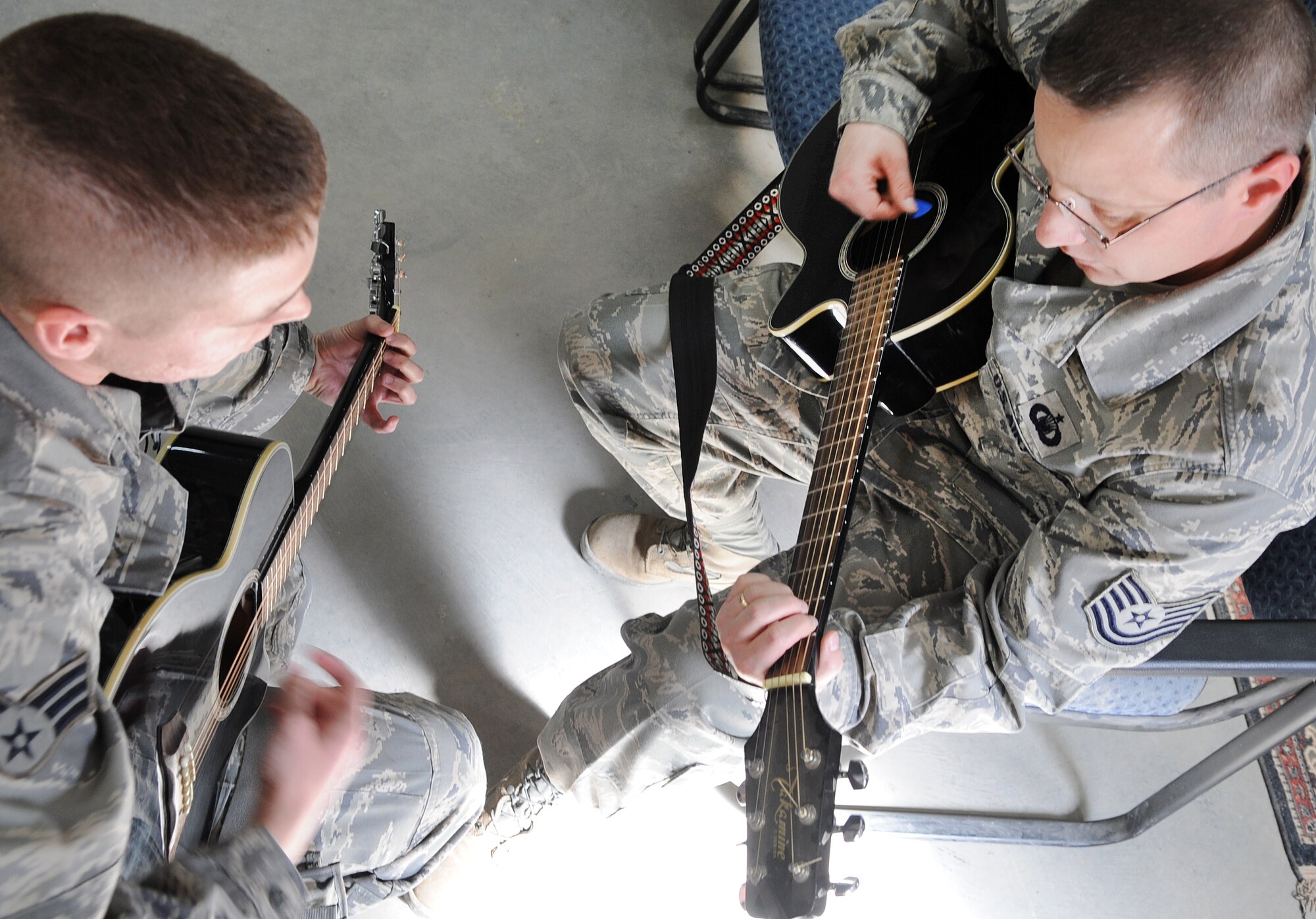 Senior Airman Blake Draper, 506th Air Expeditionary Group Commander's Support Staff, gives a guitar lesson to Tech. Sergeant Russell Dietz, 506 AEG chaplain assistant, on Kirkuk Regional Air Base, Iraq, March 22, 2010. He uses his passion for playing guitar as a positive outlet during his current deployment.  Airman Draper is deployed from Pope AFB, N.C.  (U.S. Air Force photo/Staff Sgt. Tabitha Kuykendall/Released)          