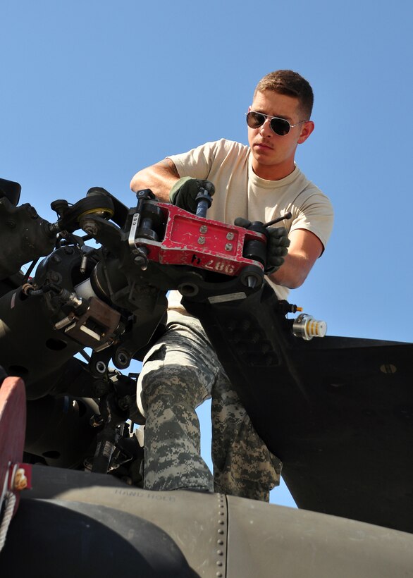 Specialist Zac Spivey, maintainer, 1st Battalion, 228th Aviation Regiment, pins the blade of a UH-60 Blackhawk March 21 as he and other members of Joint Task Force-Bravo deployed from Soto Cano Air Base, Honduras spent their first day prepping their aircraft to support Joint Task Force-Haiti.  (U.S. Air Force photo/Staff Sgt. Bryan Franks)