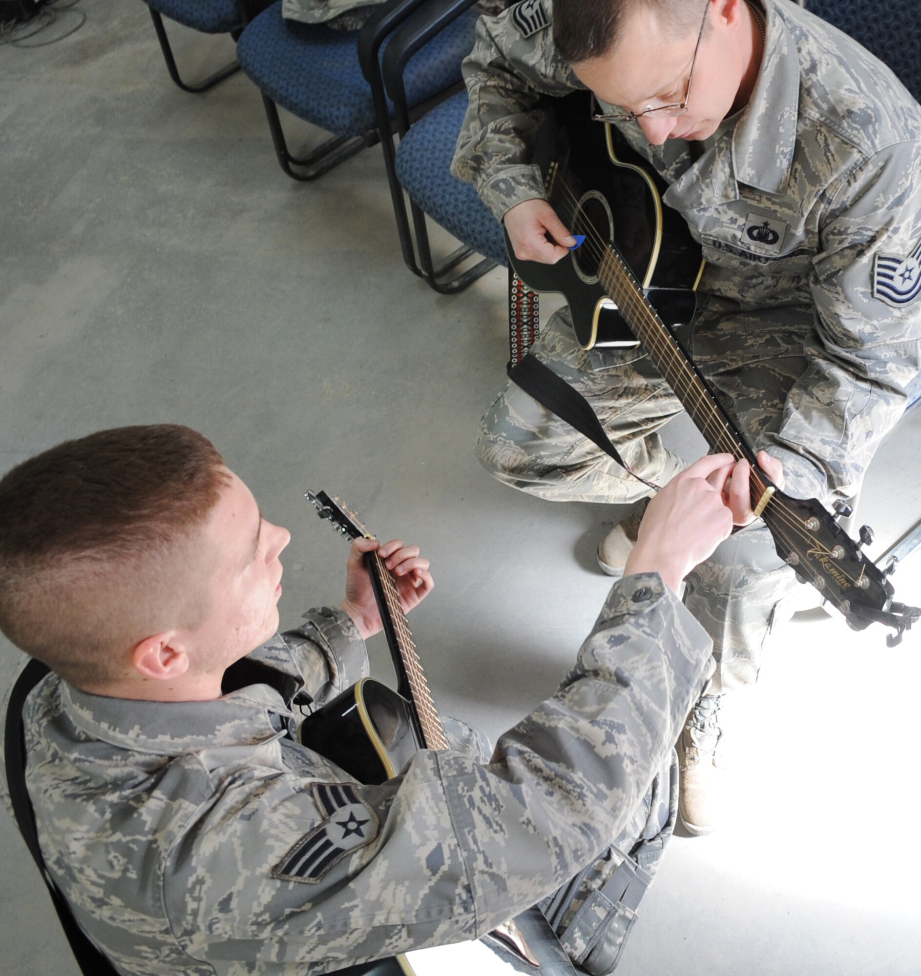 Senior Airman Blake Draper, 506th Air Expeditionary Group Commander's Support Staff, gives a guitar lesson to Tech. Sergeant Russell Dietz, 506 AEG chaplain assistant, on Kirkuk Regional Air Base, Iraq, March 22, 2010. He uses his passion for playing guitar as a positive outlet during his current deployment.  Airman Draper is deployed from Pope AFB, N.C.  (U.S. Air Force photo/Staff Sgt. Tabitha Kuykendall/Released)          