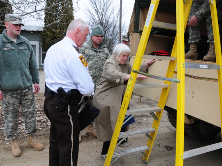 Cass County Sherriff's Department Chief Deputy Jim Thoreson helps Mili Sherman up a ladder and into a North Dakota National Guard quick response force (QRF) truck March 22, in rural Cass County. Thorson and the QRF team are assisting Sherman to temporarily vacate her home because the rising over-land flood water covering her access road has made it dangerous to drive in and out of her roadway.


