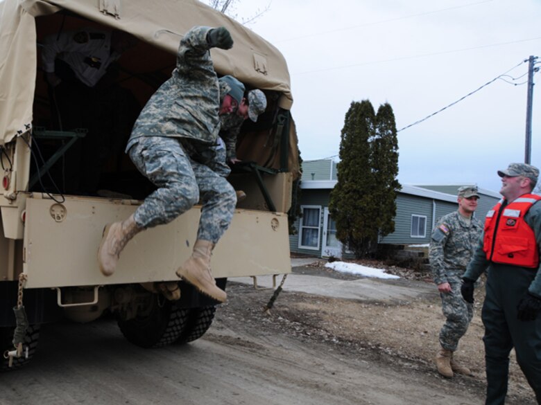 Sgt. Brian Steckler, of the 815th Engineer Company, jumps out of the back of a quick response force (QRF) truck March 22, as his QRF team responds to a request for assistance from the Cass County Sherriff's Dept.  The QRF team is assisting an elderly rural resident to temporarily vacate her home because the rising flood water has left it inaccessible to automobile traffic.


