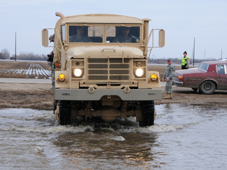 A North Dakota National Guard quick response force (QRF) truck drives through over-land flood water that is covering a rural Cass County roadway March 22, as soldiers of the 815th Engineer Company respond to a request for help by the Cass County Sherriff's Dept.  The soldiers are assisting an elderly rural resident to temporarily vacate her home because the rising flood water has left it inaccessible to automobile traffic.

