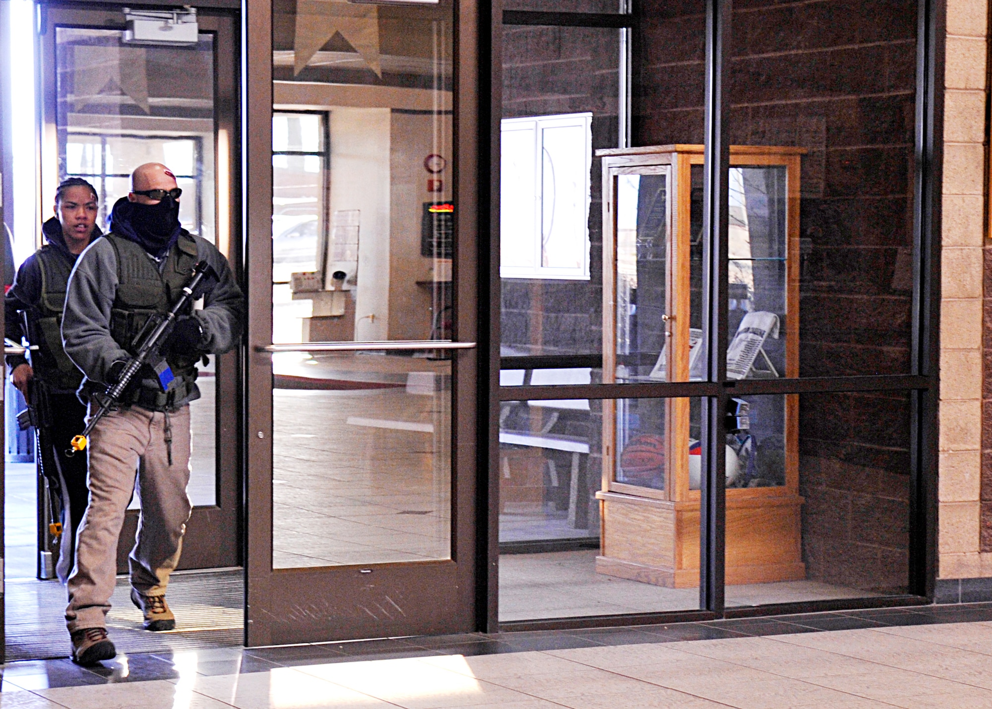Two armed gunmen, played by Tech. Sgt. David Loera and Senior Airman Lauren Moss, enter the Domenici Fitness and Sports Center March 11, 2010, at Holloman Air Force Base, N.M. The active shooter exercise evaluated how well base members are prepared for an active shooter scenario on the installation. Sergeant Lorea is assigned to the 49th Material Maintenance Group, and Airman Moss is assigned to the 49th Aeromedical Dental Squadron. (U.S. Air Force photo/Staff Sgt. Anthony Nelson Jr.)