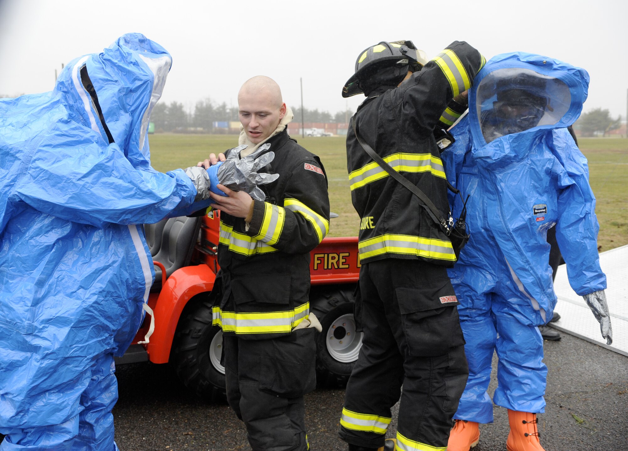 HAZMAT firefighters use the “buddy system” to don protective suits before responding to a simulated chemical spill March 15 during a HAZMAT Crisis Exercise at Joint Base McGuire-Dix-Lakehurst. The purpose of the HAZMAT Crisis Exercise is to prepare first responders for real world HAZMAT situations, and familiarize them with the tools, equipment and techniques needed to complete the mission. (U.S. Air Force photo/Carlos Cintron)
