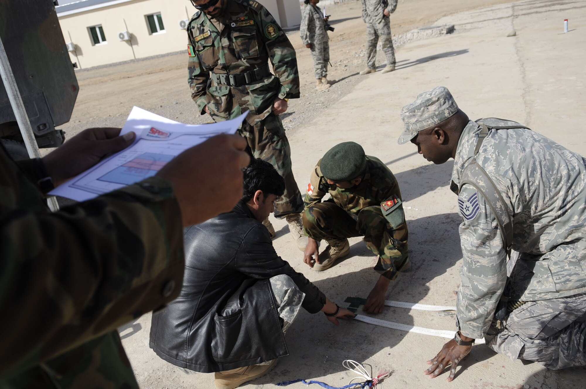 Technical Sergeant Vernon Jones, DCST—Task Force Phoenix medical advisor to the Kandahar Regional Military Hospital, assists members of the Afghan National Army as they construct a volleyball court to increase morale for their soldiers, March 1, at Camp Hero, Kandahar Airfield, Afghanistan. (U.S. Air Force photo by Senior Airman Nancy Hooks/Released)
