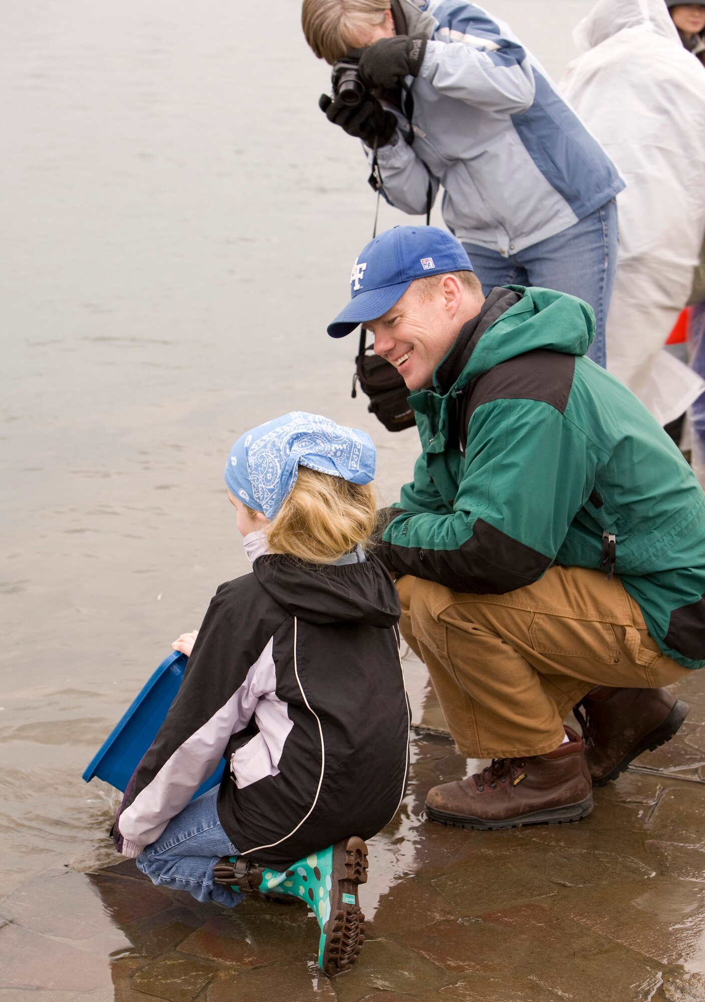 ORIASE TOWN, Japan -- Lindsey Simpson and her parents Lt. Col. Anthony Simpson, 35th Operations Support Squadron assistant director of operations, and Blythe Simpson, release baby salmon into Oriase River March 20. The annual release of baby salmon into the river gives Misawa families a chance to teach ecological conservation to their children. (Courtesy photo/David Crumley)