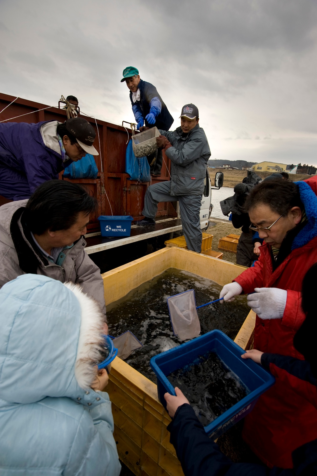 ORIASE TOWN, Japan -- Members of the 35th Civil Engineer Squadron natural resources management office and Oriase Town office unload and distribute baby salmon to volunteers during the 14th Annual Baby Salmon Release at Salmon Park March 20. These salmon are released annually to help replenish the population that makes up a key part of the Japanese ecosystem. (U.S. Air Force photo/Staff Sgt. Samuel Morse)