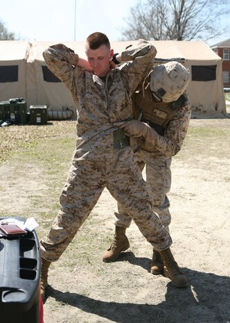 Cpl. Matthew Gardner (rear), a motor transport operator and Corporal of the Guard, Combat Logistics Battalion 8, 2nd Marine Logistics Group, searches a Marine before entry into the Command Operations Center during the battalion's Command Post Exercise held at Camp Lejeune, N.C, March 22-25, 2010.  The battalion conducted the exercise to simulate command and control operations in preparation for their future deployment to Afghanistan.