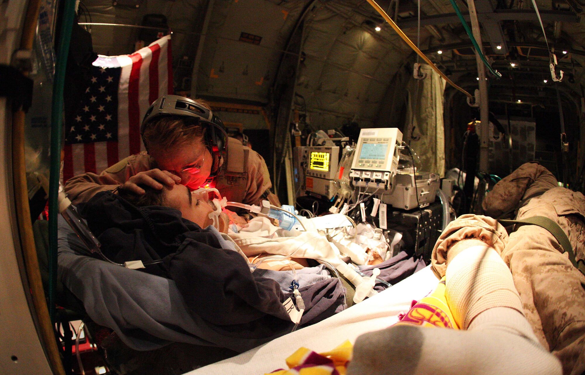 452nd Aeromedical Staging Squadron nurse Maj. Deborah "Lucy" Lehker comforts a wounded Canadian Army soldier Feb. 14, 2010, aboard a C-130 on an emergency airlift between Kandahar and Bagram.  Independent combat journalist Michael Yon, a former Green Beret, was aboard the flight to capture the image, which has circulated across the world via the Web.  (Photo courtesy of Michael Yon/www.michaelyon-online.com)