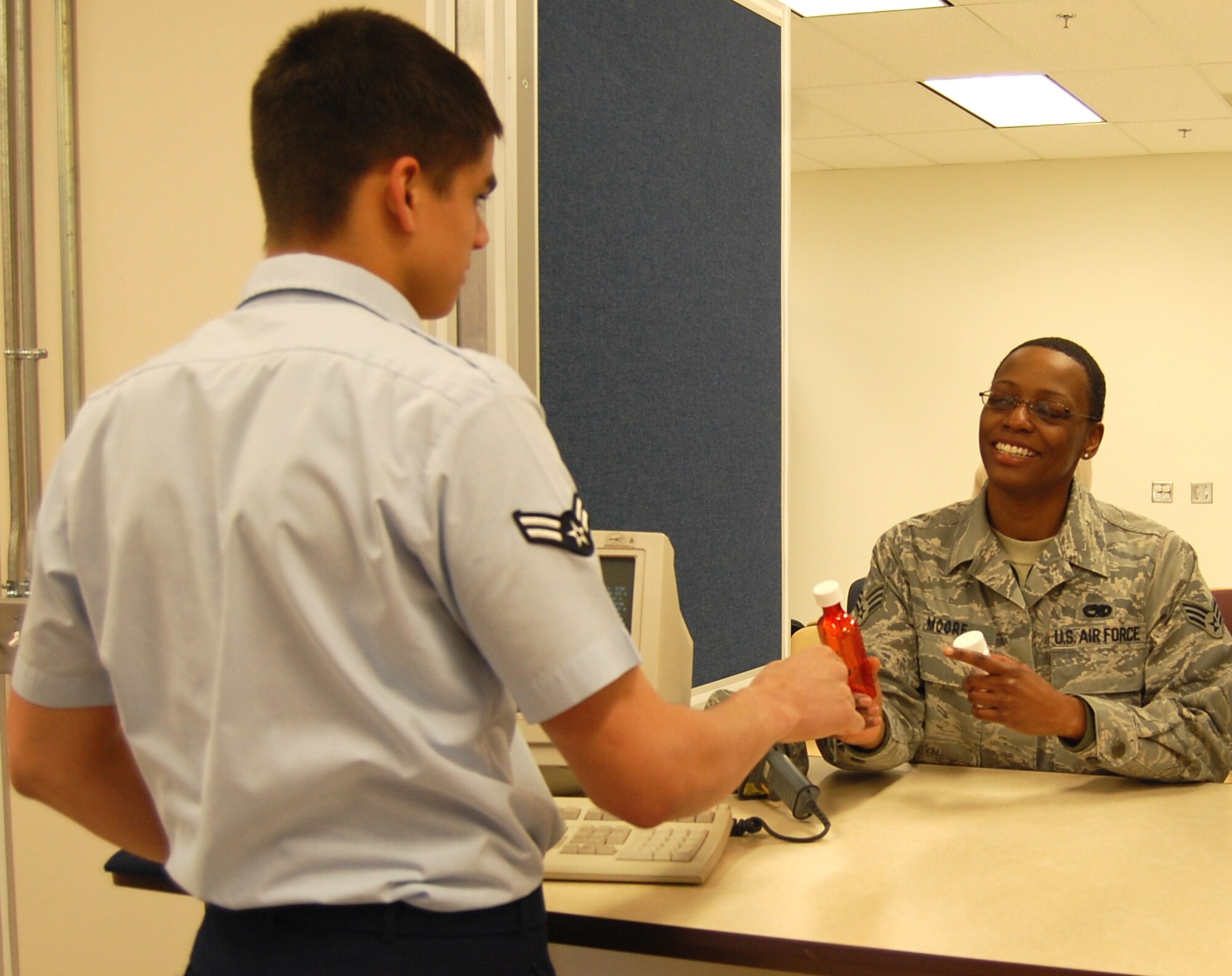 Airman 1st Class Andrij Bondarenko, 81st Diagnostics and Therapeutics Squadron pharmacy technician, hands Senior Airman Karen Moore, 403rd Wing, her prescription shortly after  8 a.m. Monday as she became the first customer to use the new satellite pharmacy’s indoor service. The new facility has state-of-the art robotics and automated prescription dispensing equipment to enhance patient safety and processing time.  (U.S. Air Force photo by Steve Pivnick)