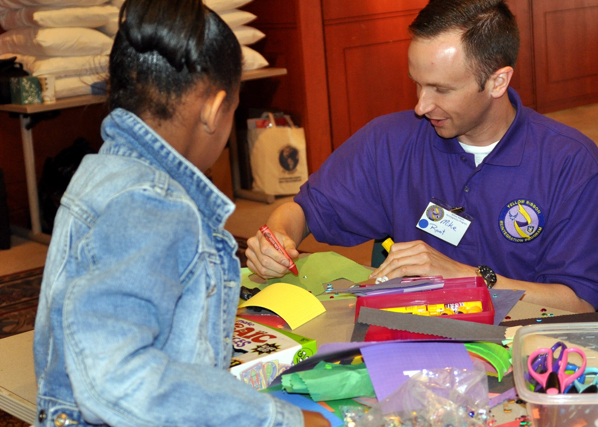 Tech. Sgt. Michael Root, a mission readiness noncommissioned officer for the 917th Logistics Readiness Squadron on Barksdale Air Force Base, La., aids an Air Force dependant in decorating her homemade greeting card for her recently deployed parent during a Yellow Ribbon Reintegration Program event March 20, 2010. Sergeant Root was one of the volunteers at the event at the American Airlines Training and Conference Center in Fort Worth, Texas, and was assigned to the youth activities section.  (U.S. Air Force Photo/Senior Airman Crystal Marie Jordan)