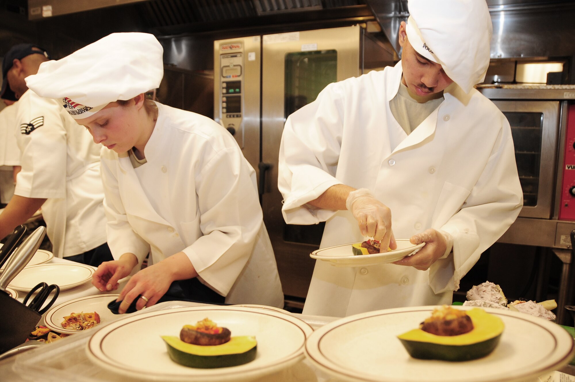 Airmen 1st Class Sarah Meador (left) and Michael Azares put the final touches on their appetizers during the "Ellsworth Iron Chef" competition March 17, 2010, at Ellsworth Air Force Base, S.D. The competition consisted of four teams competing against each other to complete three dishes in one hour. Airmen Meador and Azares are 28th Force Support Squadron cooks. (U.S. Air Force photo/Airman 1st Class Anthony Sanchelli)
