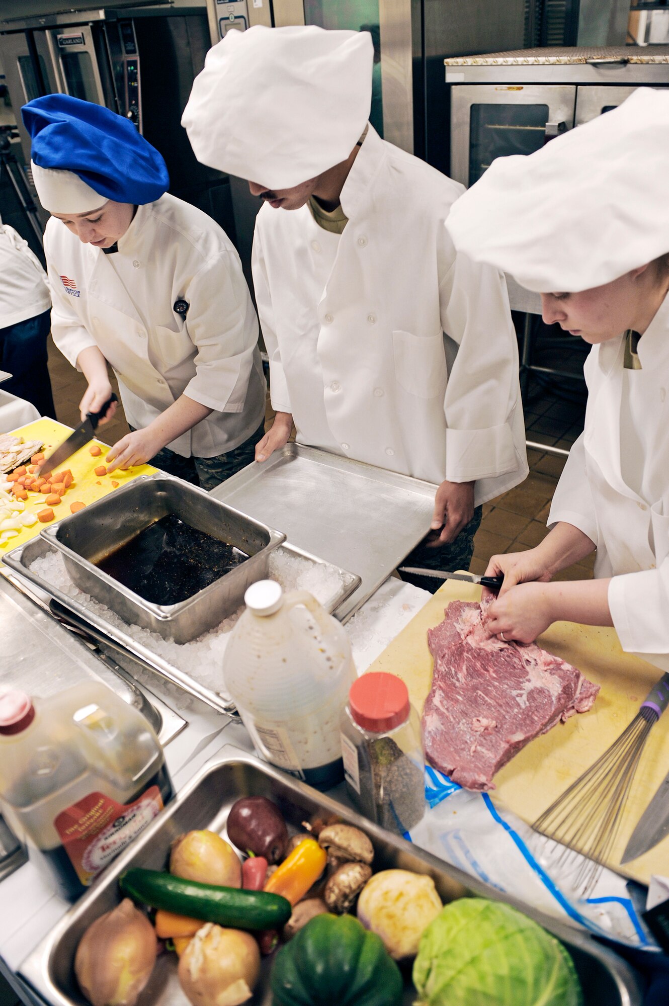 (From left) Airmen 1st Class Steffanie Whipple, Michael Azares and Sarah Meador prepare a teriyaki corned beef for the second annual "Ellsworth Iron Chef" competition March 17, 2010, at Ellsworth Air Force Base, S.D. Their dishes consisted of stuffed mushrooms, Cajun fish, teriyaki steak and whipped fruit. Airmen Whipple, Azares and Meador are 28th Force Support Squadron food services technicians. (U.S. Air Force photo/Senior Airman Marc I. Lane)