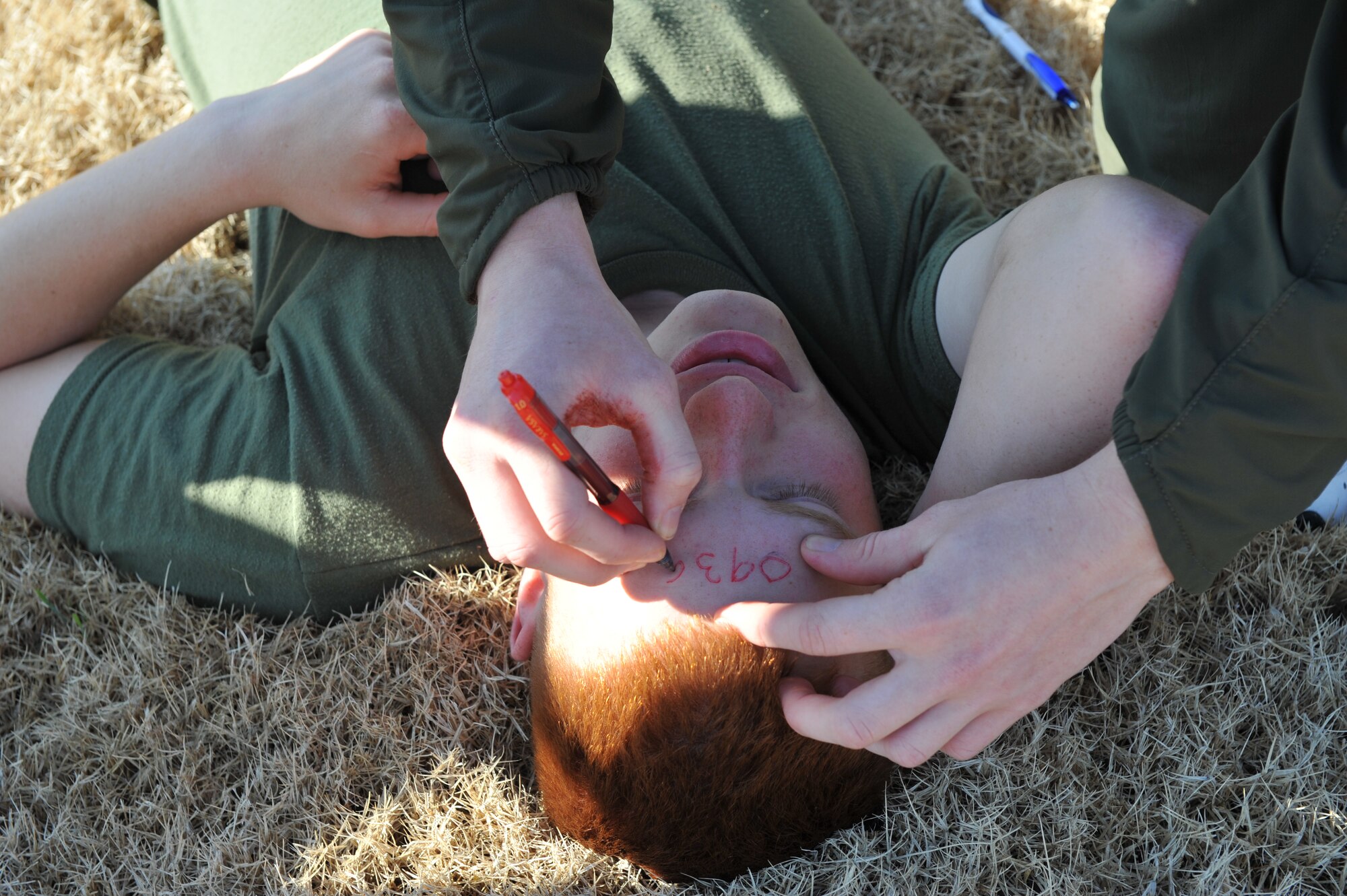Pfc. Nicholas Snyder writes the time he placed a tourniquet on Marine Private First Class Kyler Farley, both Marine Detachment Four barracks members,  after Private Farley was injured during a simulated bomb explosion March 19 outside of Little Rock Air Force Base Headquarters building. (U.S. Air Force Photo by Senior Airman Chris Willis)