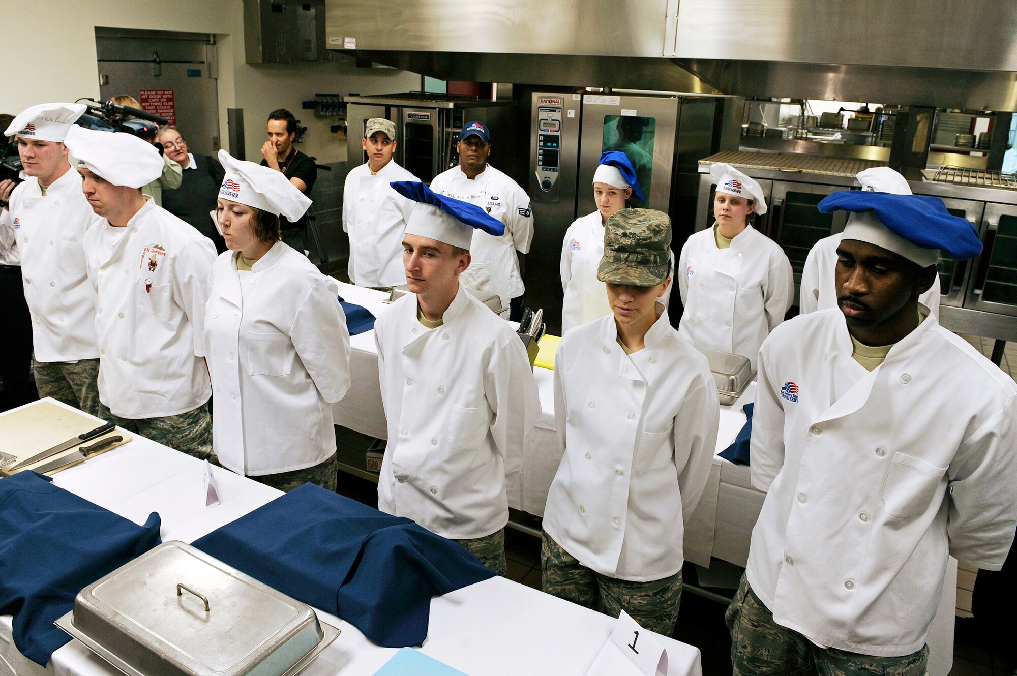 Four, three-person teams stand ready to begin the second annual "Ellsworth Iron Chef" competition March 17, 2010, at Ellsworth Air Force Base, S.D. The teams had one hour to prepare three dishes using corned beef, milkfish, cabbage, peppers, mushrooms, fruits, parsnips, turnips and onions into an appetizer, entr?e and dessert. (U.S. Air Force photo/Senior Airman Marc I. Lane)