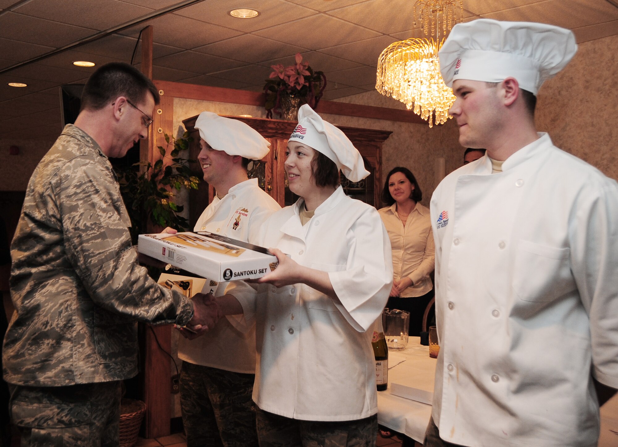 Col. Steven Hiss (left) presents Airmen 1st Class Tiffany Lamb and Brent Smith and Airman Reese Audette with a four-piece knife set during the "Ellsworth Iron Chef" competition March 17, 2010, at Ellsworth Air Force Base, S.D. The competition was an hour-long competition between four teams preparing three dishes with an Irish twist. Colonel Hiss is the 28th Bomb Wing vice commander, and Airmen Lamb, Smith and Audette are 28th Force Support Squadron cooks. (U.S. Air Force photo/Airman 1st Class Anthony Sanchelli)