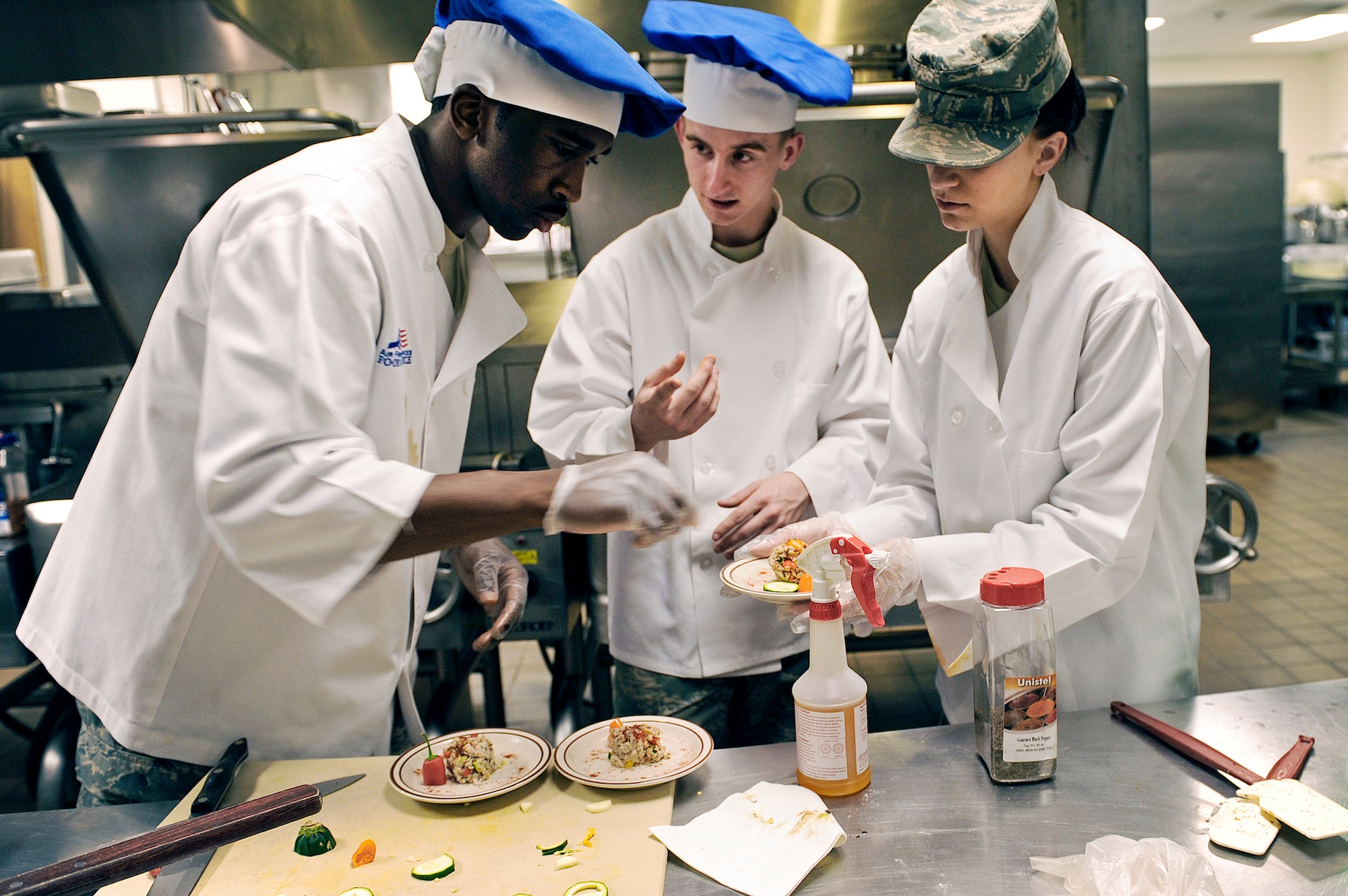 Airman 1st Class Desmond Boone (from left to right), Airman Anthony Bruhl and Airman 1st Class Ashleigh Morford prepare a milkfish entr?e during the second annual "Ellsworth Iron Chef" competition March 17, 2010, at Ellsworth Air Force Base, S.D. The teams had one hour to prepare three dishes using corned beef, milkfish, cabbage, peppers, mushrooms, fruits, parsnips, turnips and onions into an appetizer, entr?e and dessert. Airmen Boone, Bruhl and Morford are 28th Force Support Squadron food services technicians. (U.S. Air Force photo/Senior Airman Marc I. Lane)