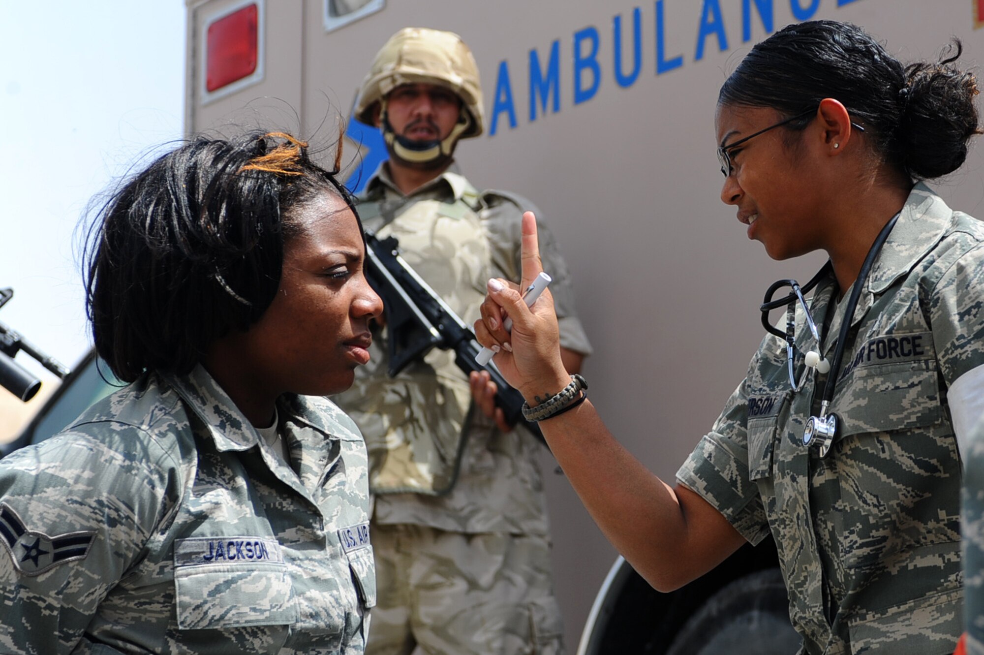 Senior Airman Tina Anderson (right), 379th Expeditionary Medical Group medical technician, evaluates a mock hostage, while a host-nation member provides security, during an exercise scenario at a non-disclosed Southwest Asia location March 23, 2010. (U.S. Air Force photo by Senior Airman Kasey Zickmund)[RELEASED]