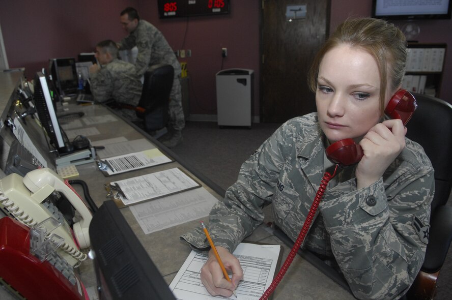 MINOT AIR FORCE BASE, N.D. -- Airman 1st Class Kaysi Craig, 5th Operations Support Squadron airfield management operations coordinator, responds to the primary crash net alert phone at base operations March 19. Airfield management crew members manage and maintain all flight line operations in support of the B-52H Stratofortress as well as all 5th Bomb Wing aircrew personnel. (U.S. Air Force photo by Senior Airman Jesse Lopez)
