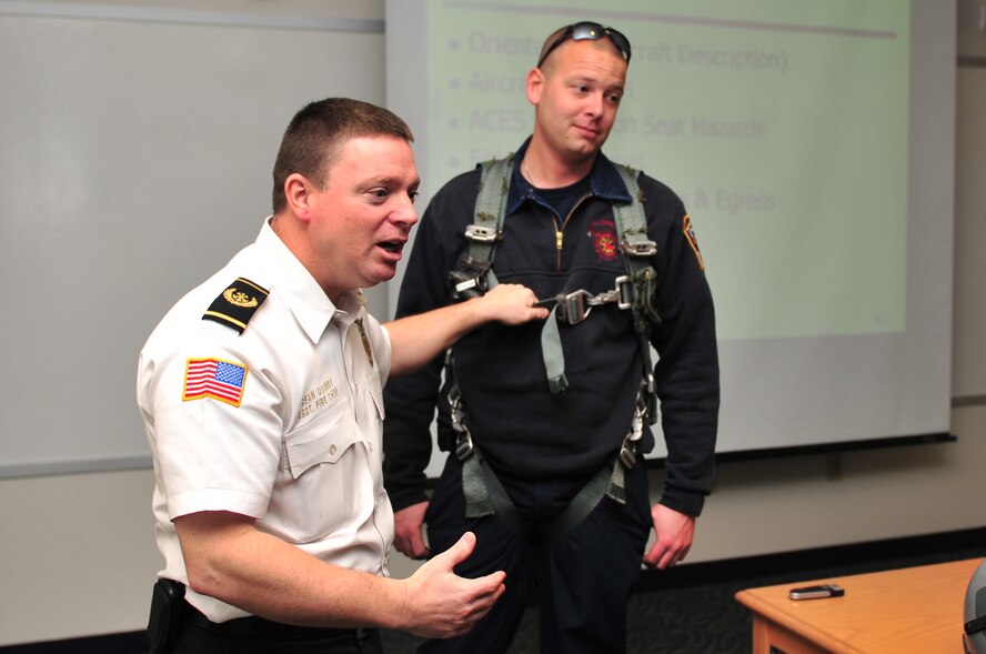 Sean Quinby, 4th Civil Engineer Squadron assistant fire chief, and Scott Matthews, Goldsboro firefighter, demonstrate gear worn by aviators during mission familiarization training at Seymour Johnson Air Force Base, N.C., March 19, 2010. During the class, Goldsboro and Wayne County firefighters learned the best methods to approach a downed aircraft and how to protect the community from associated fires. In the case of an off-base emergency, these firefighters will primarily focus on fighting structural fires. Quinby hails from Seattle and Matthews hails from Winston, N.C. (U.S. Air Force photo/Senior Airman Rae Perry)