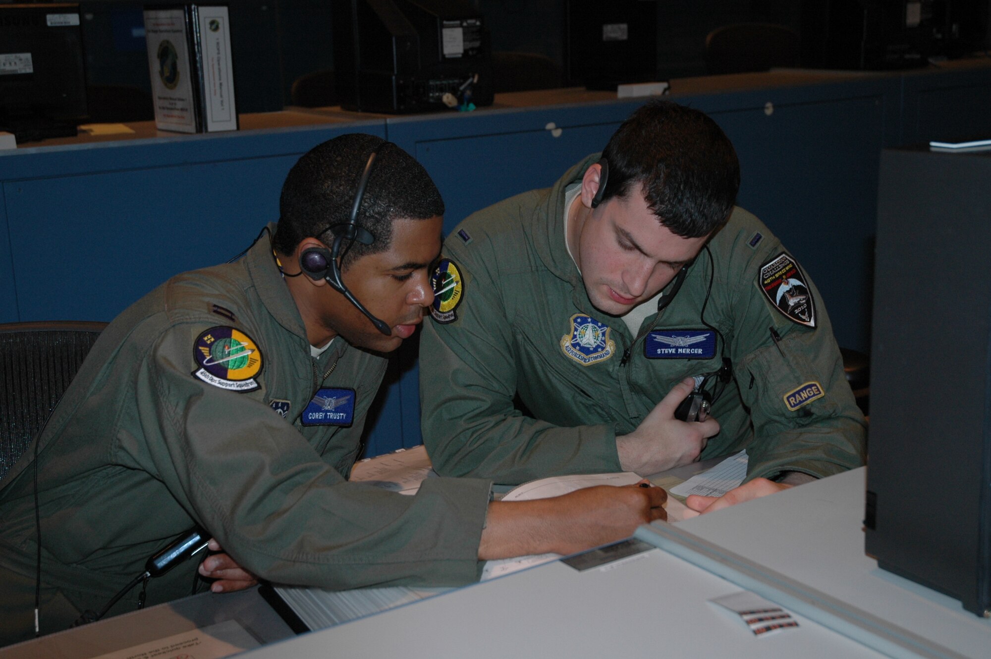 Capt. Corey Trusty and 1st Lt. Steve Mercer of the 45th Operations Support Squadron look up information during a simulated launch sequence during practice for the Guardian Challenge March 18 in the Morell Operations Center on Cape Canaveral Air Force Station. (U.S. Air Force photo/Senior Airman David Dobrydney)